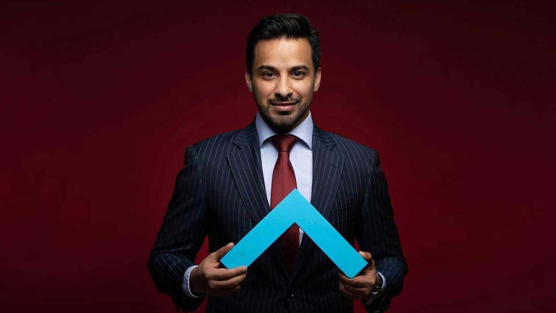 CEO of Perpetual Group holding the company’s blue logo, wearing a formal suit on a red background